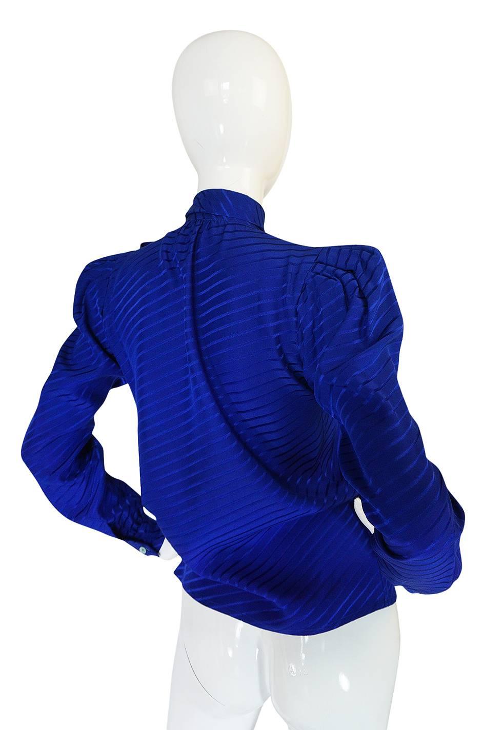 This is a classic signature look, silk secretary blouse by Yves Saint Laurent done in a beautiful rich blue silk with a angled line woven through the fabric. The silk is cut on the bias so once it is on the body the top moves and drapes perfectly as