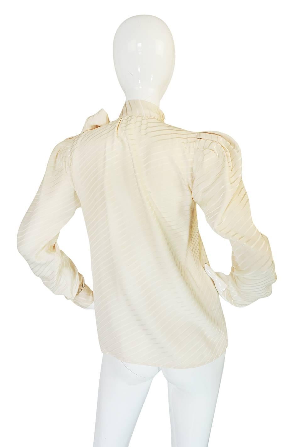 This is a classic signature look, silk secretary blouse by Yves Saint Laurent done in a beautiful rich cream silk with a angled line woven through the fabric. The silk is cut on the bias so once it is on the body the top moves and drapes perfectly