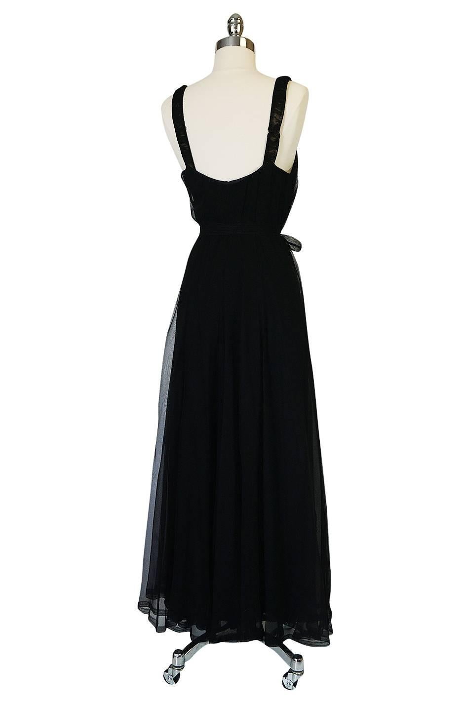 This beautiful and unique piece is wonderful and a personal favorite. It is an incredible late twenties, early thirties gown that is made of a fine black silk chiffon with an inner silk lining and feels heavenly once on. It is entirely cut on the