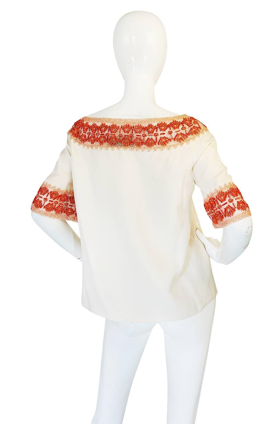 This is an extraordinary find. It is a stunning piece of Valentino with an extensive detailing of coral beading mixed with tube beads hand applied on silk netting and then used as detailing on the cream silk base. Valentino made this coral look