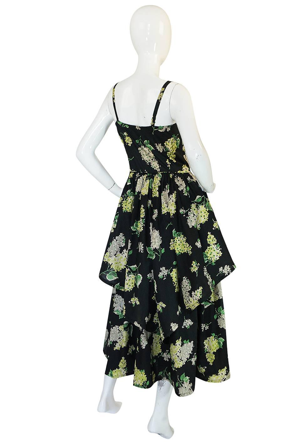 This stunning dress that dates to the late forties, early 1950s combines a beautiful print and color combination with sequins and a pretty feminine feel. The entire dress is stunning and made of a beautiful black cotton voile with a pretty floral