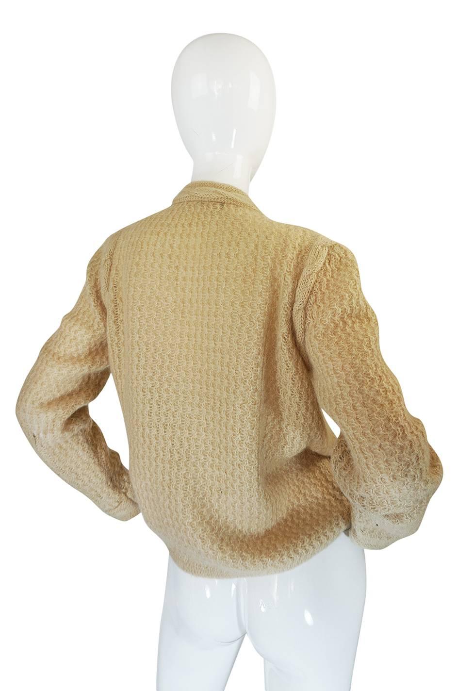 This is a fantastic Chanel knit cardigan made from a wool that feels like it has just a touch of mohair in it so that it has a wonderful soft and cozy feel. This is classic Chanel and instantly recognizable as being from the house with its gold logo