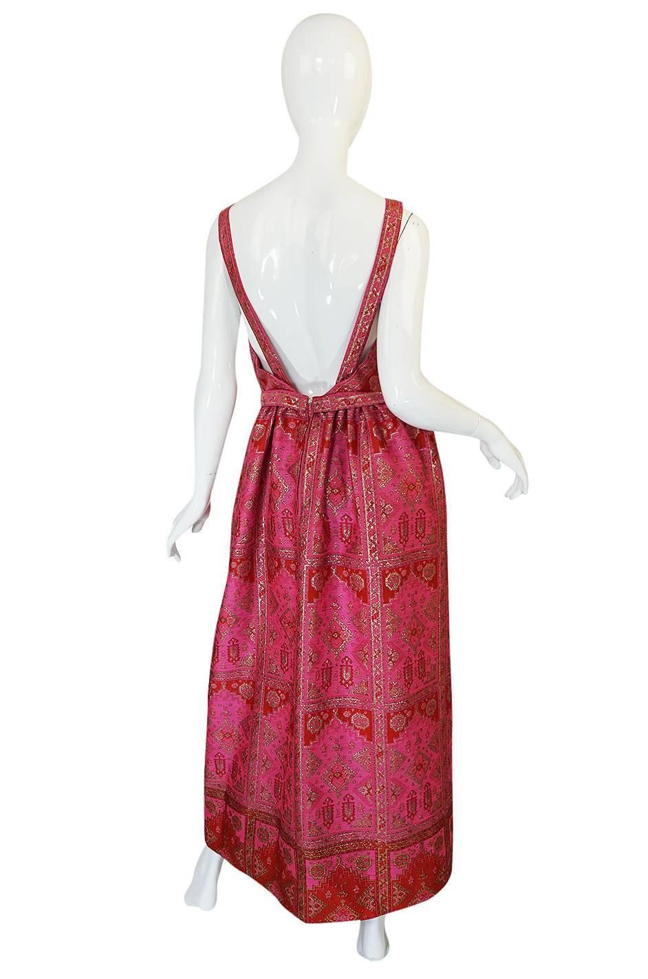 This stunning gown has no labels but feels like a label piece in its construction. It is definitely a higher end piece and a beautiful from this time period. It is made from a fabulous pink brocade that has a gold thread worked through the pattern