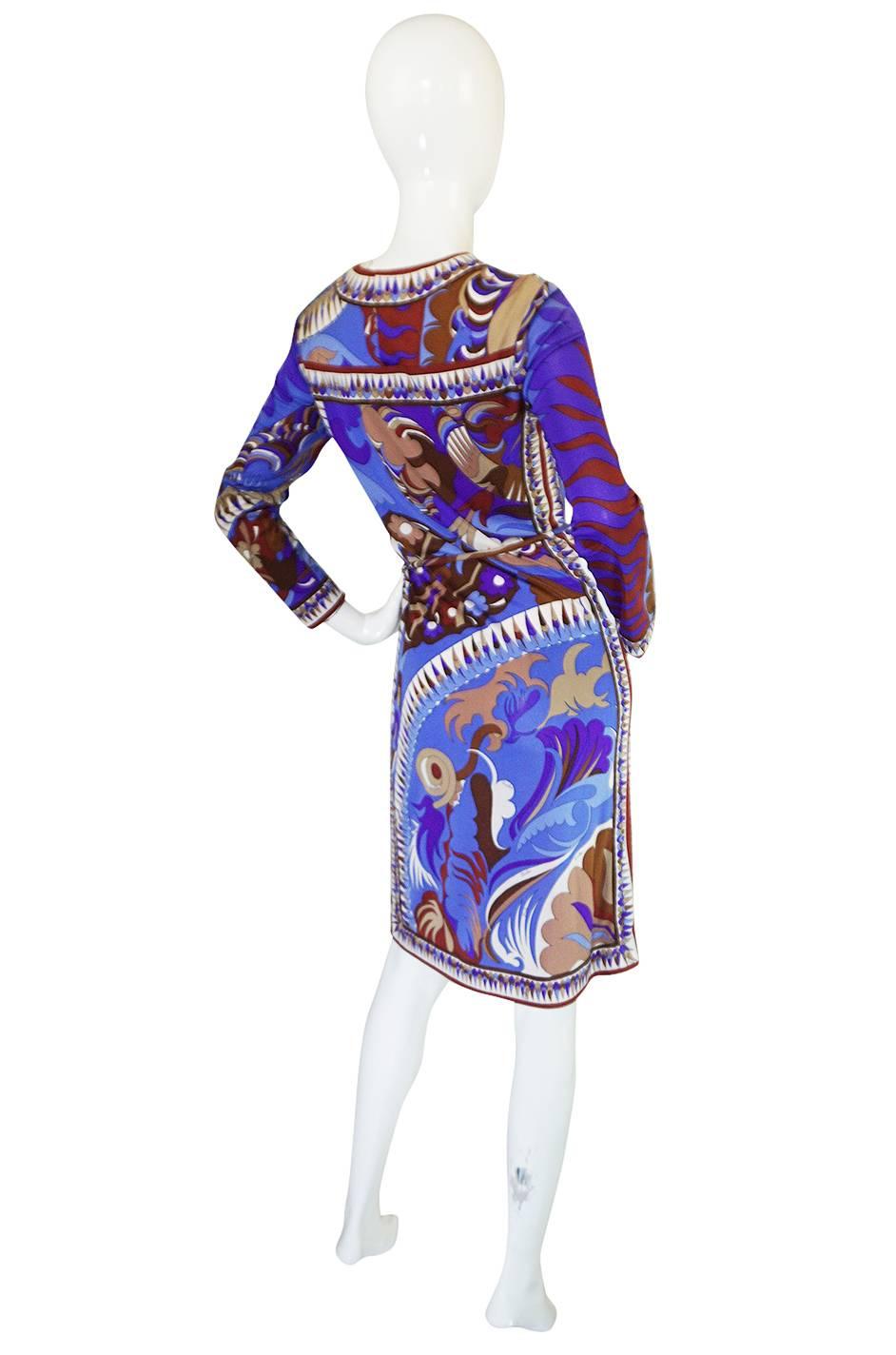 What a beautiful Pucci dress that is constructed from one of his signature silk jerseys with a bright pattern in a coveted mix of blues, lavender and taupes that absolutely pops off the black backdrop. The bodice skims over the bust right down to