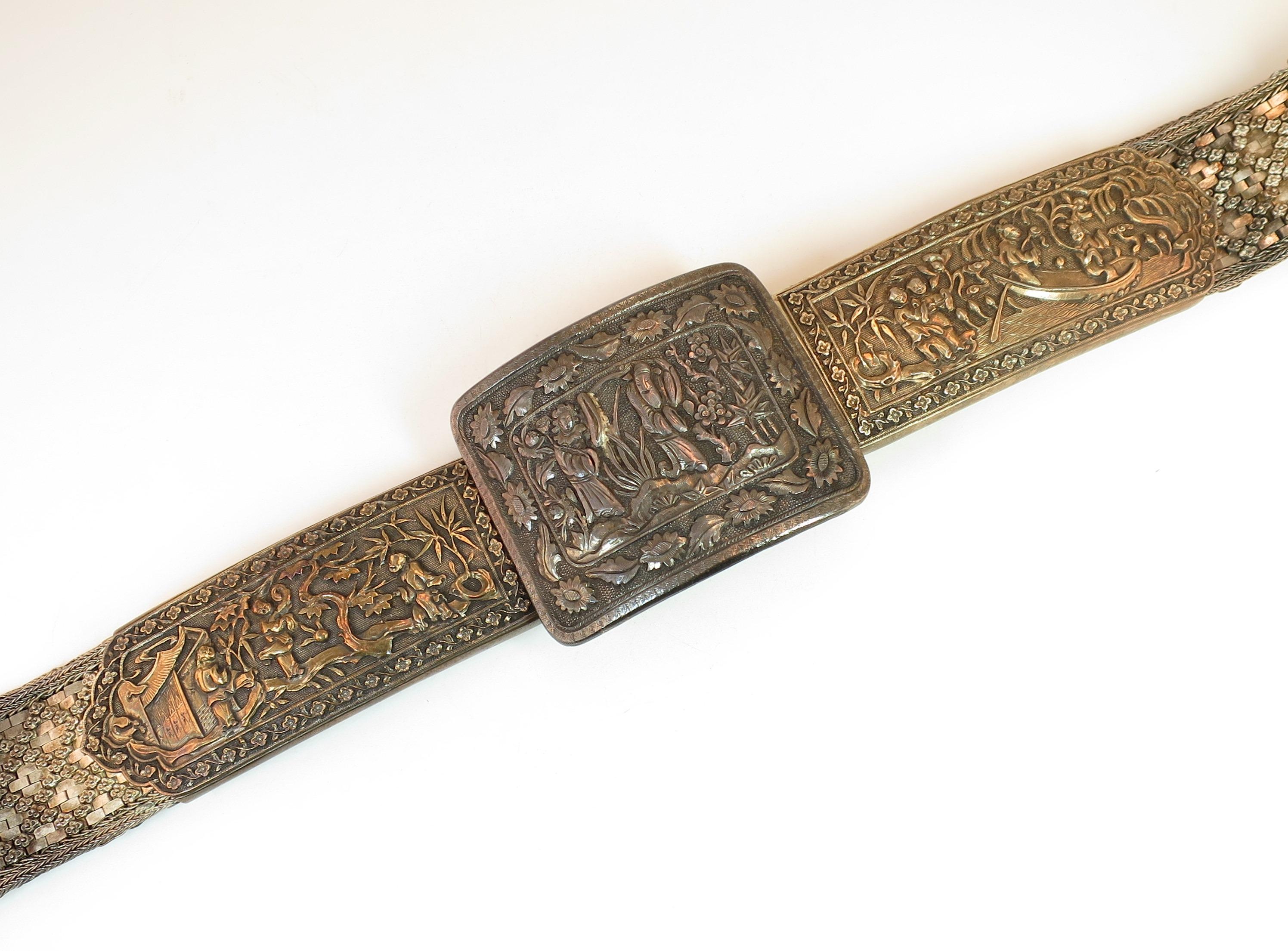 Offered here is an early 19th century Asian silver belt of tightly-woven flat dense geometric mesh embellished with a crisscross design of tiny floral studs. The large rectangular curved buckle is flanked by two large gold-washed elongated panels,