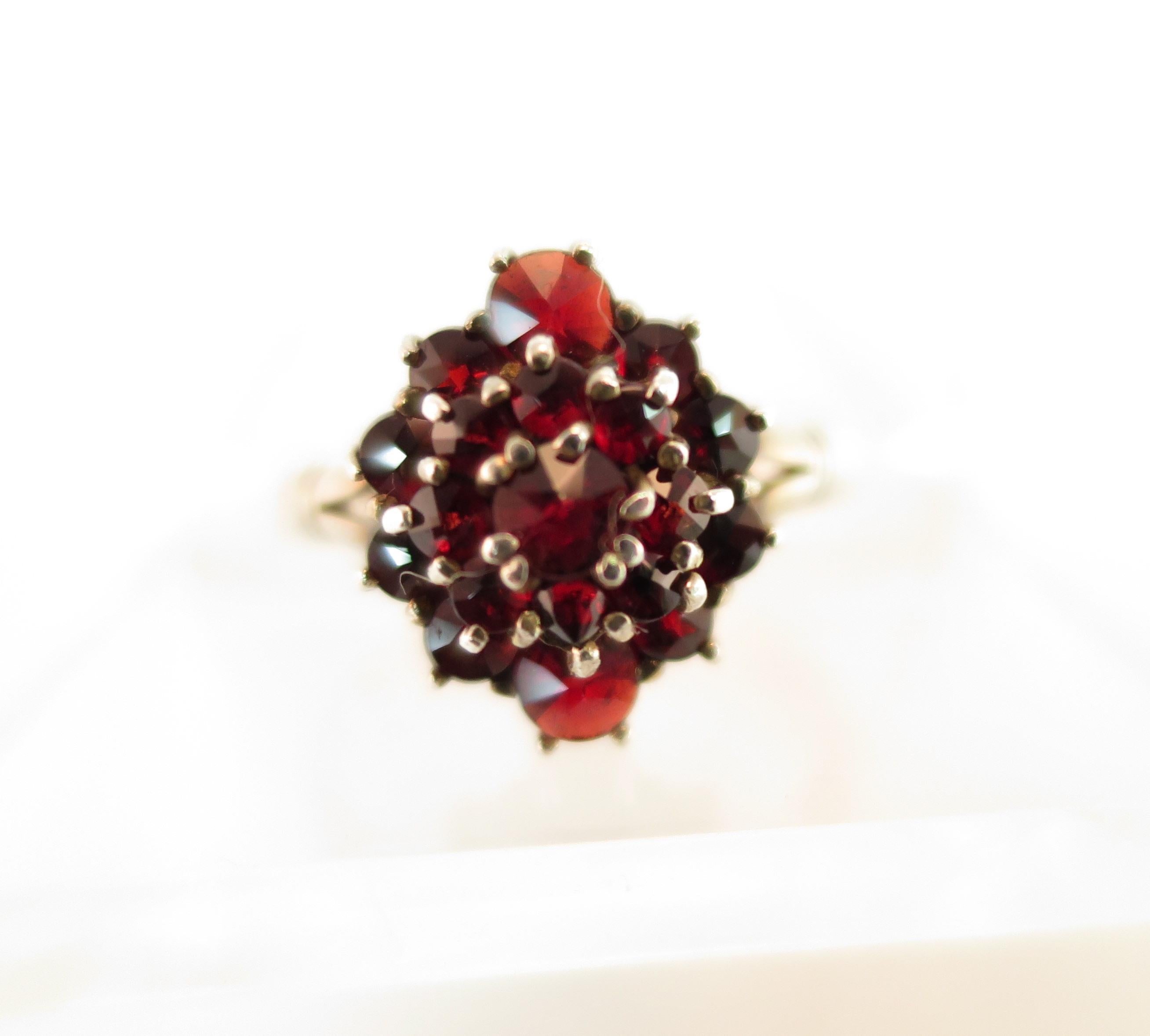 Offered here is a delicate Victorian ring of 900 silver set with rose-cut Bohemian pyrope garnets. The smooth band has etched horizontal bars where it splits slightly at the ends to meet the tiered platform that sparkles with prong-set stones above