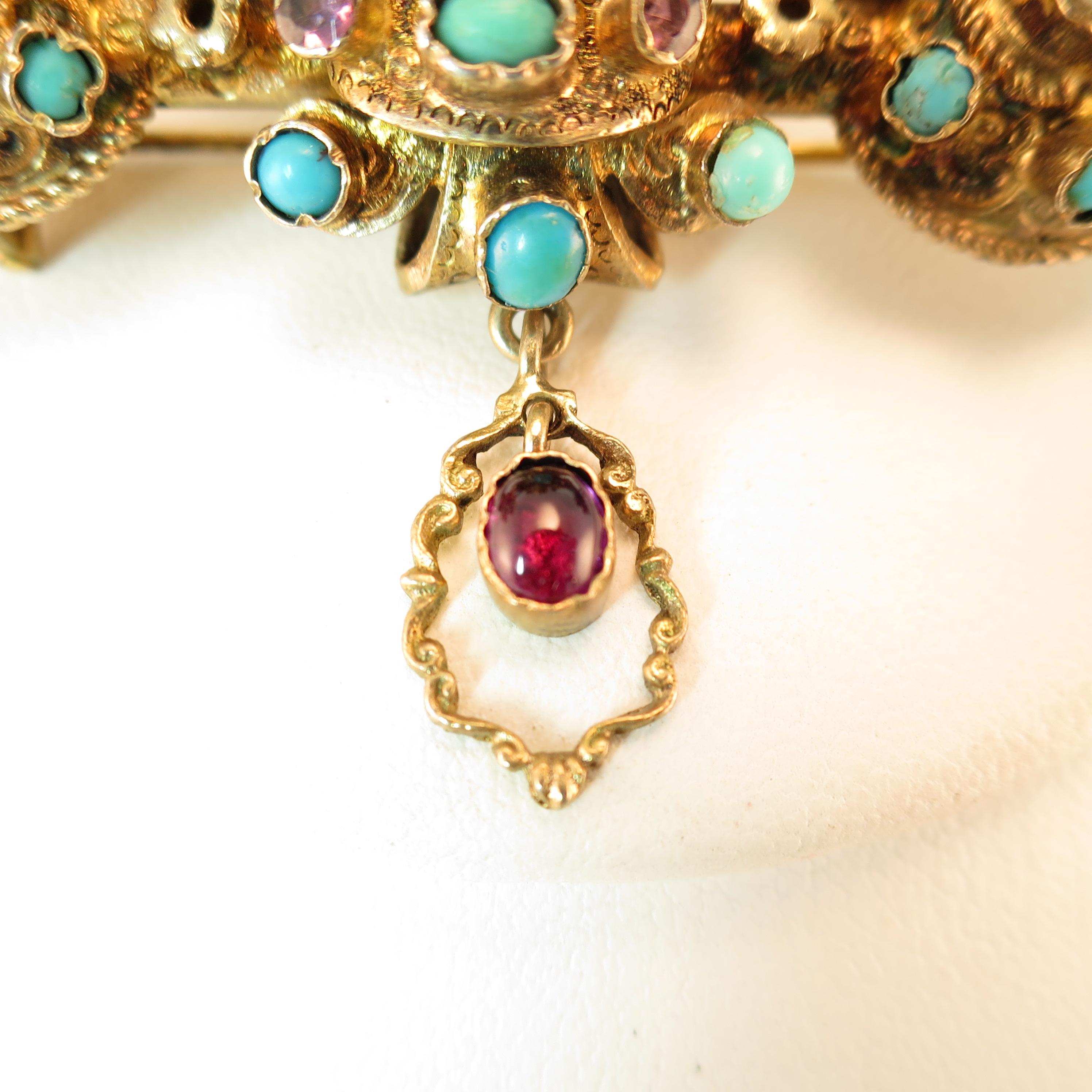 Offered here is a Georgian brooch of solid 10k gold in a deeply three-dimensional baroque design, Circa 1840. The main portion of the brooch is embellished with crimped-bezel-set amethysts, turquoise, garnet, and pearls; below is an etched dangle