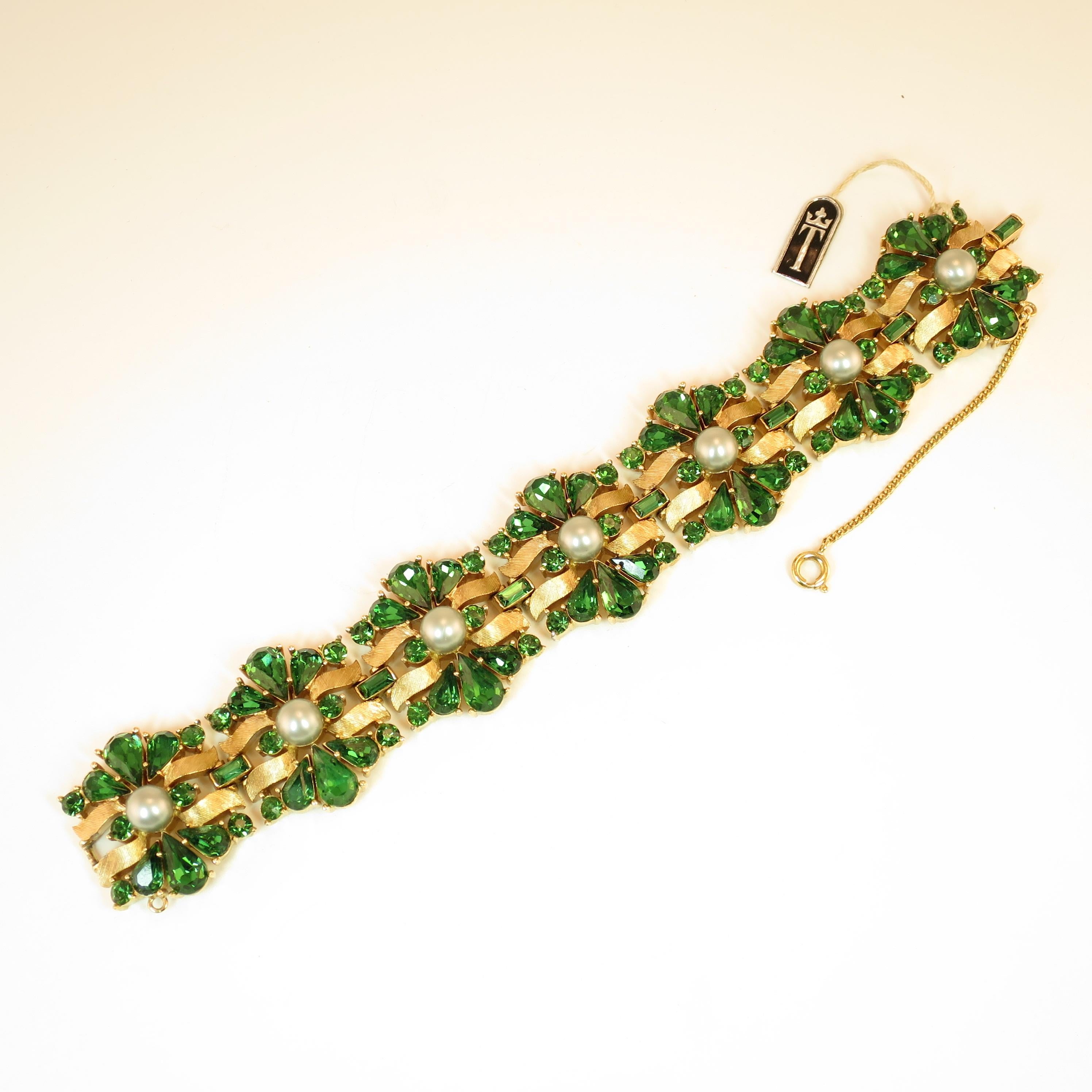 Offered here is a Crown Trifari Alfred Philippe-designed heavily-gilded rhodium bracelet embellished with emerald Swarovski crystals and silver glass pearls from the 1950s. The heavy link design presents slightly domed stations in a flowing