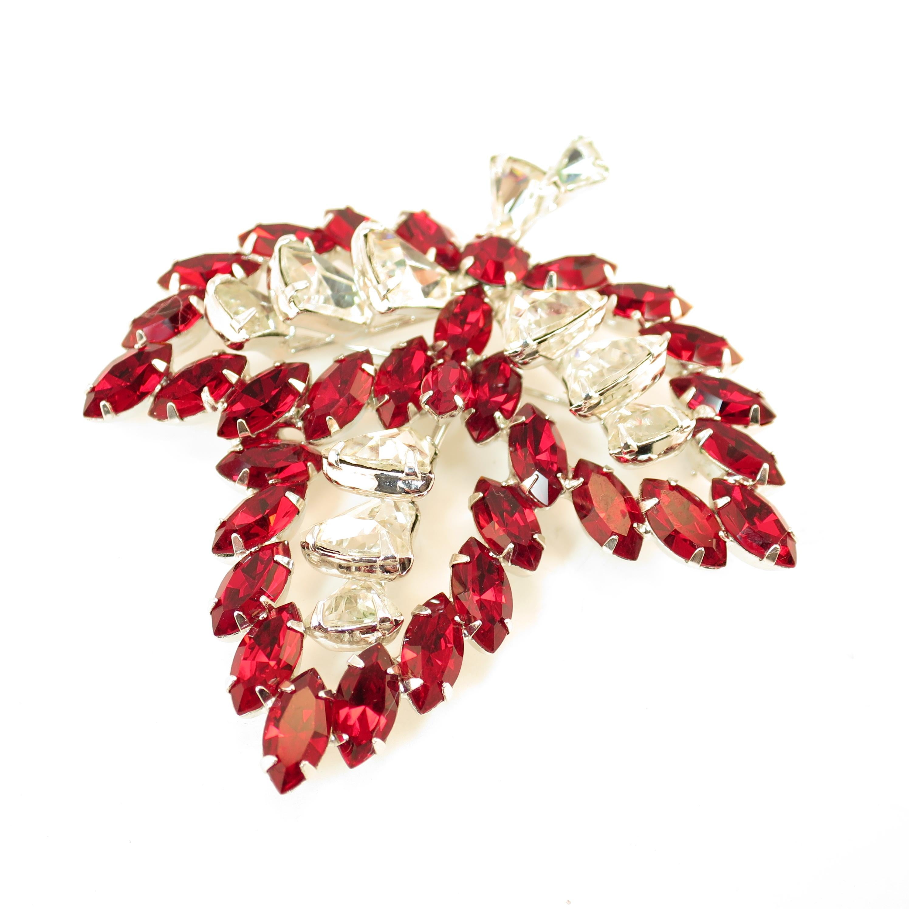 Offered here is a Vendome rhodium-plated brooch embellished with Austrian crystals from the 1950s. The three-dimensional tripartite leaf design presents deep-ruby marquise stones outlining the leaf, surrounding a center of fancy-cut bell-shaped