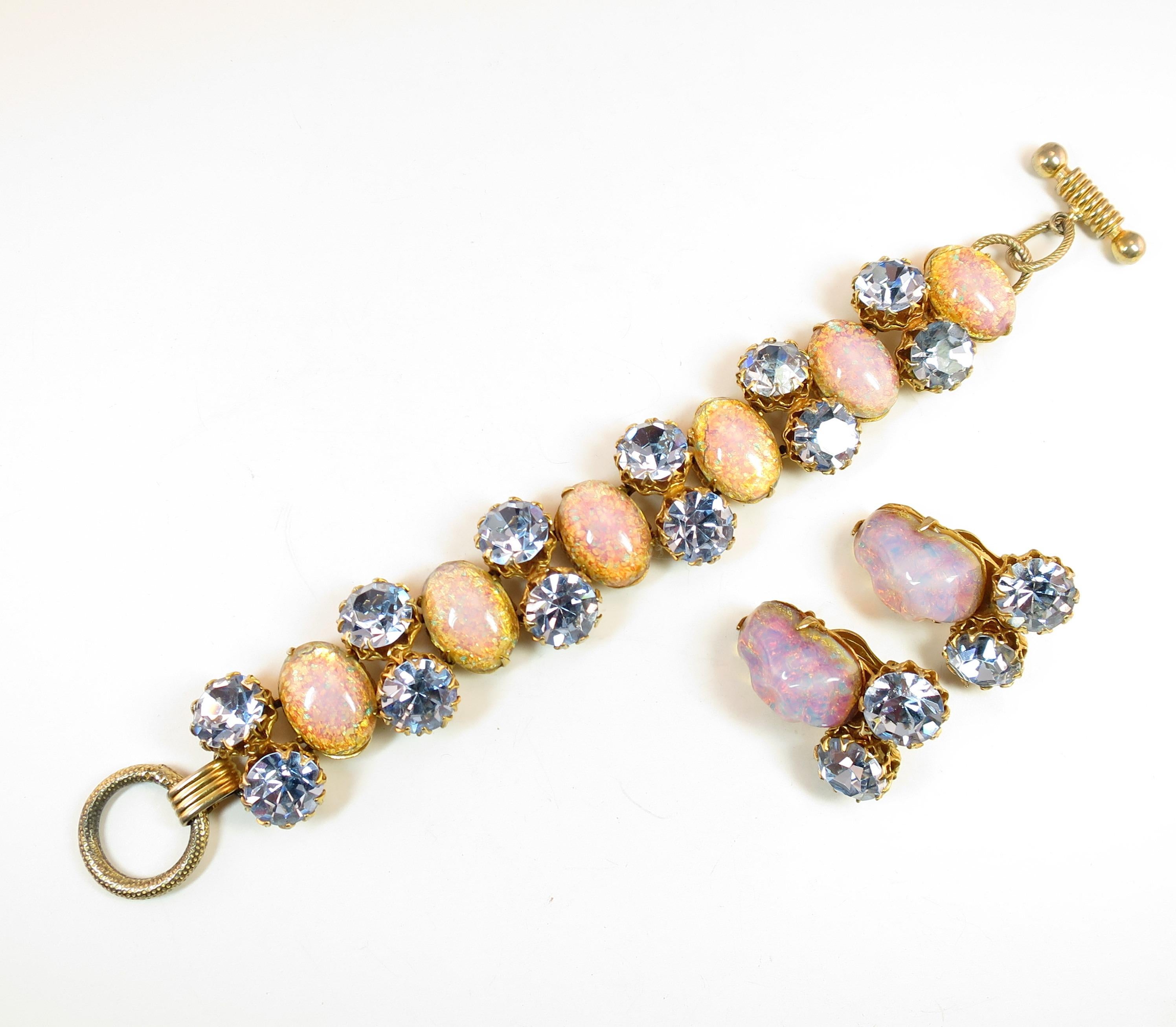 Offered here is a Schiaparelli demi-parure of gold-plated bracelet and clip-back earrings from the 1950s. The segmented design of the bracelet presents oval cabochons of opal art glass alternating with pairs of crown-prong-set faceted blue crystals;