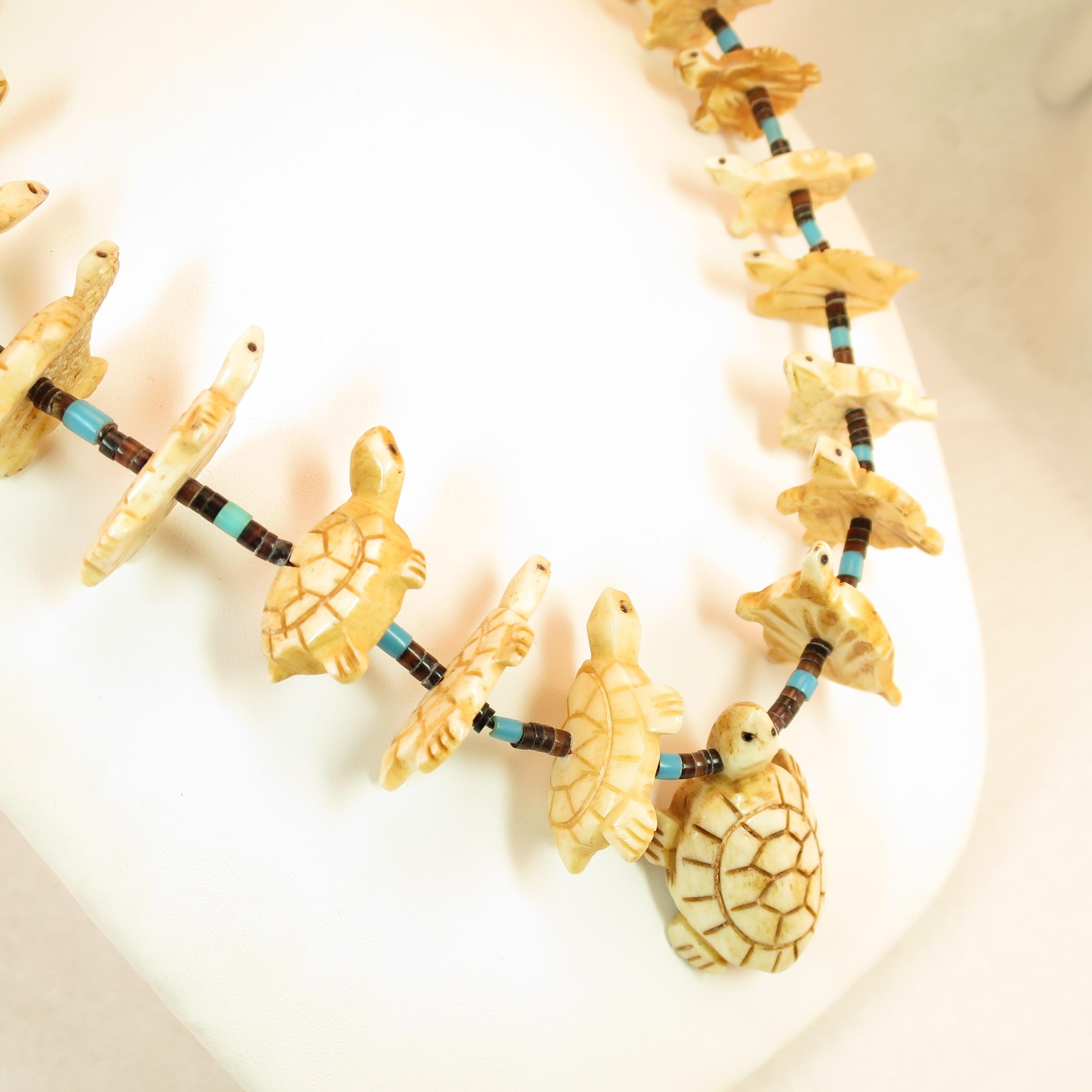 Offered here is a Native American Zuni handcrafted fetish necklace from the 1970s. Rows of graduated horizontally-set bone turtle fetishes are intricately carved and dyed, inlaid with tiny jet eyes. The fetishes are separated by strands of turquoise