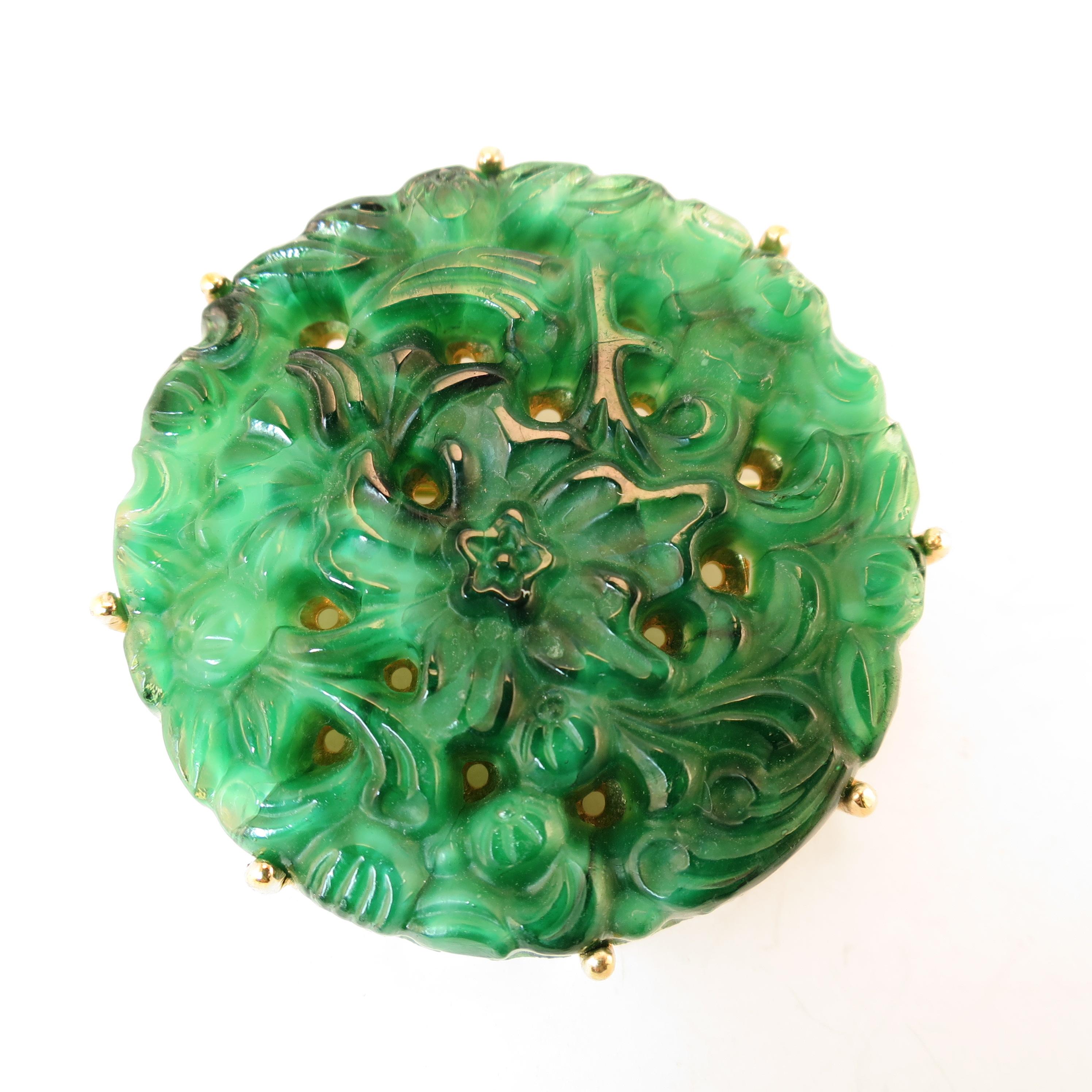 Offered here is a Ciner Asian-design jade glass gold-plated brooch and matching clip-back earrings from the 1950s. Thick circular discs of carved perforated glass in an Asian foliate design mimicking jade are prong-set on circular open-work
