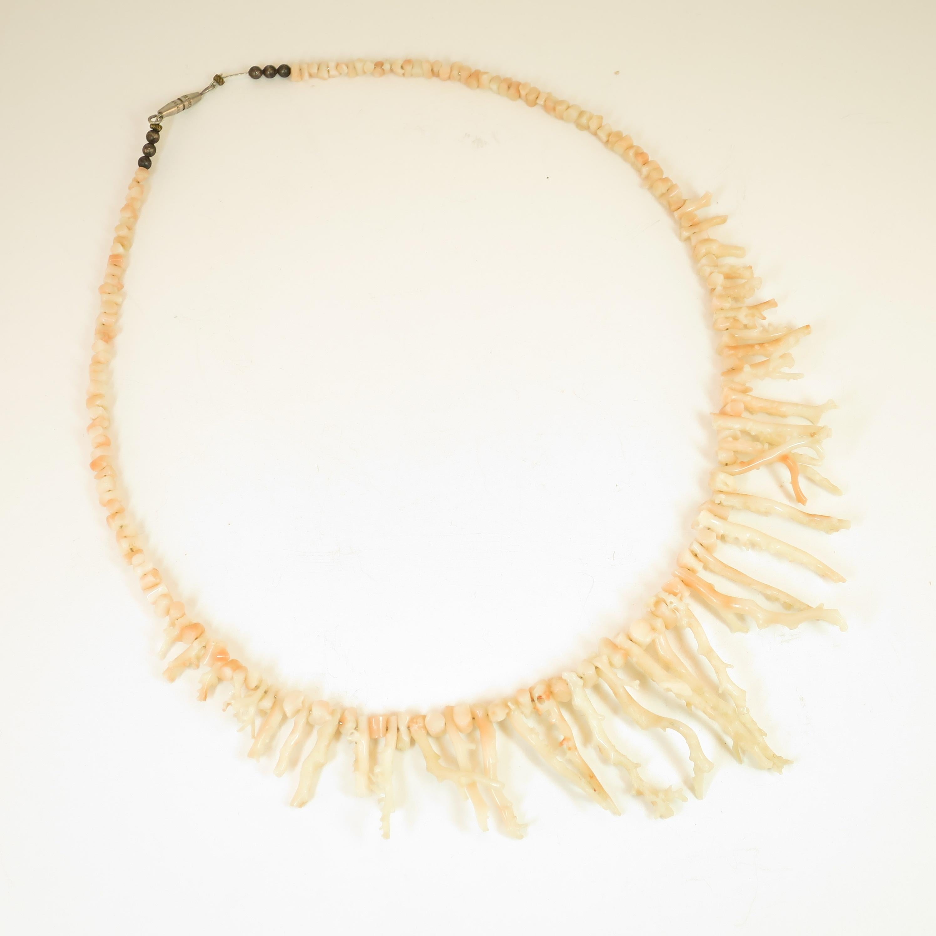Offered here is an angel skin branch coral necklace from the 1930s. Graduated angel-skin coral branches and nuggets in a delicate hue of cream blushed with pale pink are strung on secure fine wire, finished with tiny metal beads and a narrow barrel