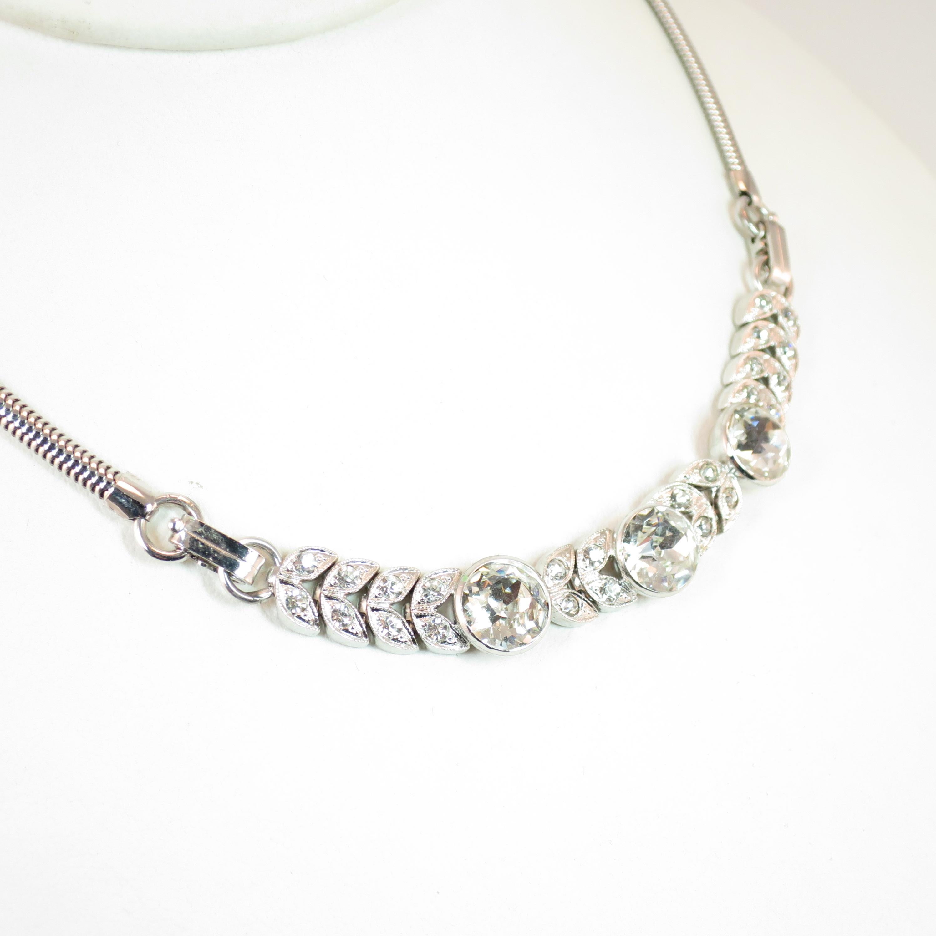 Offered here is an Engel Bros. Art Deco rhodium-plated sterling silver necklace from the 1930s. This uniquely designed necklace presents a centerpiece of large intricately faceted crystals in bezeled cup settings flanked by pavé-set small stones in