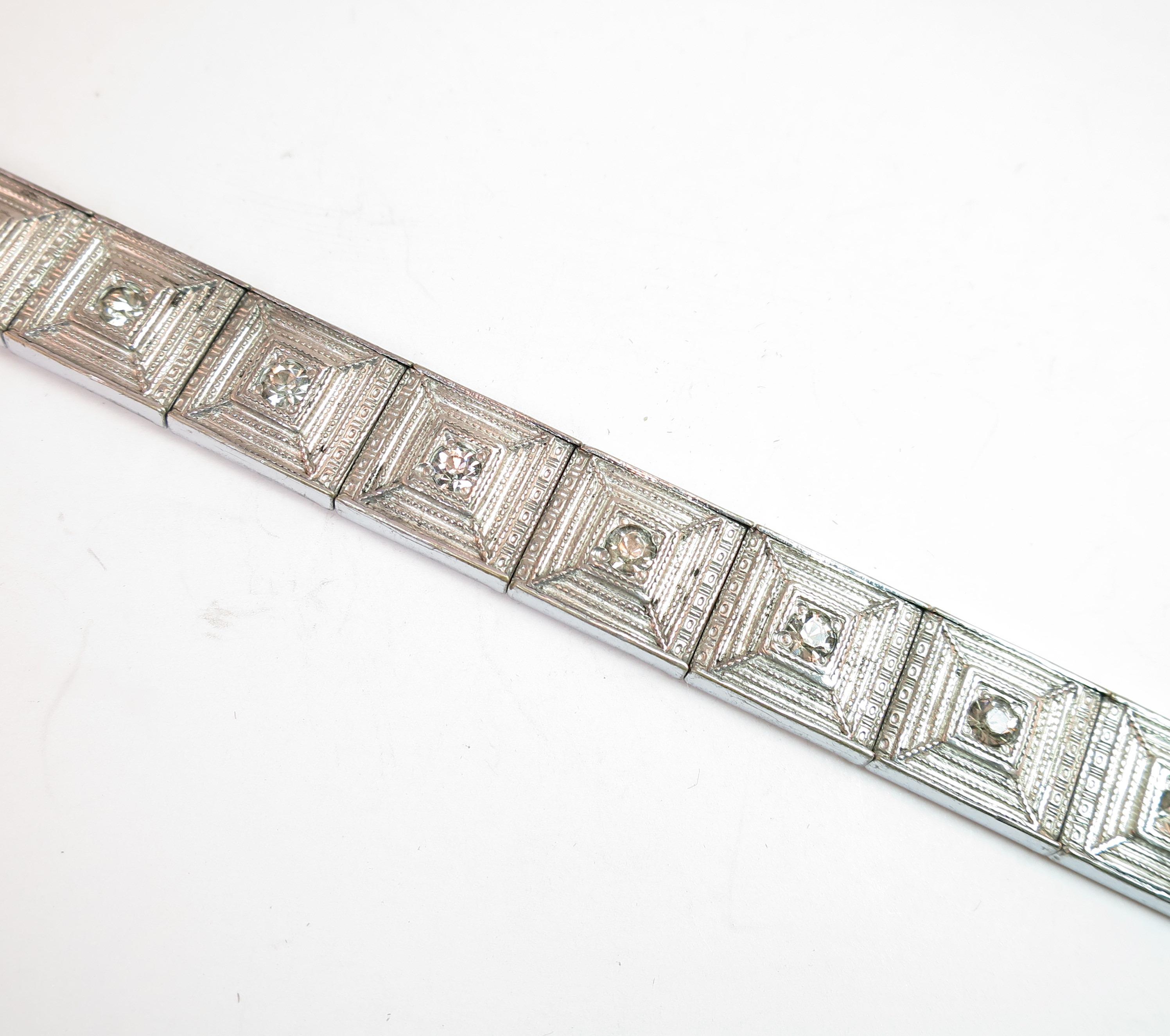 Offered here is ALLCO Art Deco rhodium-plated link bracelet created by the A.L. Lindroth Company of North Attleboro, Mass. in the 1920s. Tightly-linked square platforms are etched with a slightly pyramidal concentric design flanked by bands in a