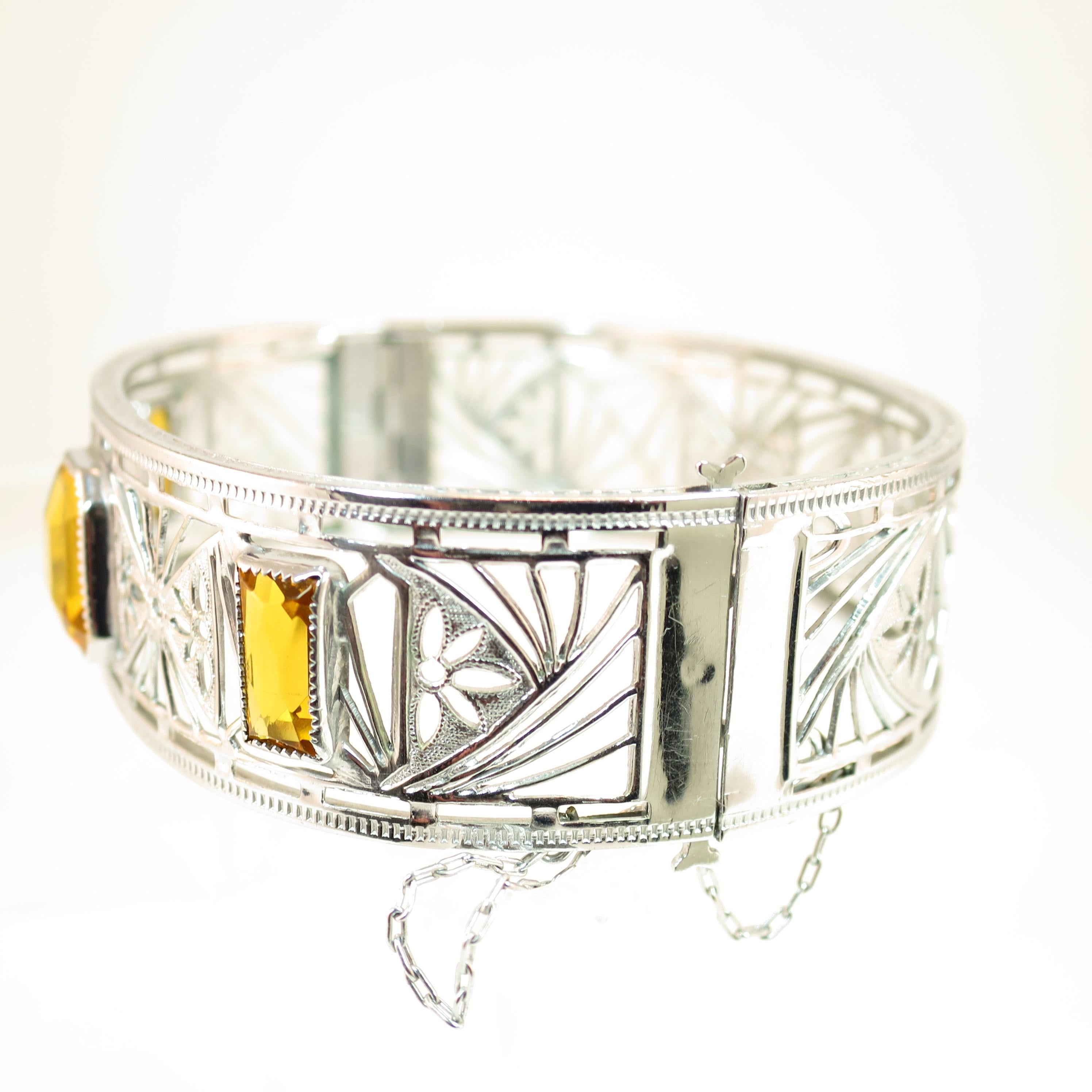 Offered here is an Art Deco Nu-Wite rhodium-plated hinged cuff bracelet created by the Ripley & Gowan Co. of Attleboro, MA in the 1920s. The overall shape is a slightly flattened oval; the wide band is decorated in a delicate spiderweb filigree with
