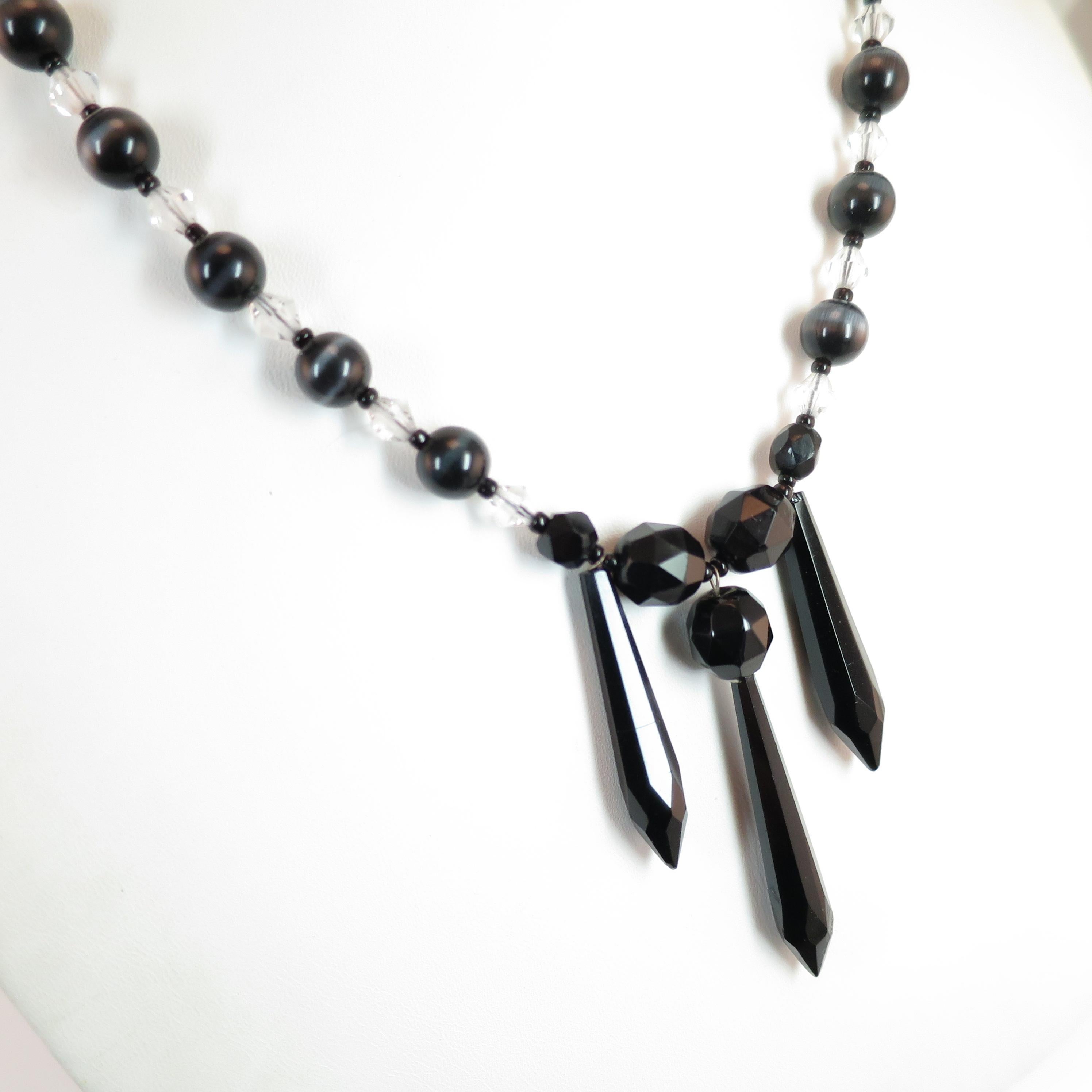 Offered here is a Victorian mourning necklace & matching drop earrings from the 1890s. The necklace presents a centerpiece of faceted French jet black glass beads above three elongated faceted jet drops; to either side there are strands of polished