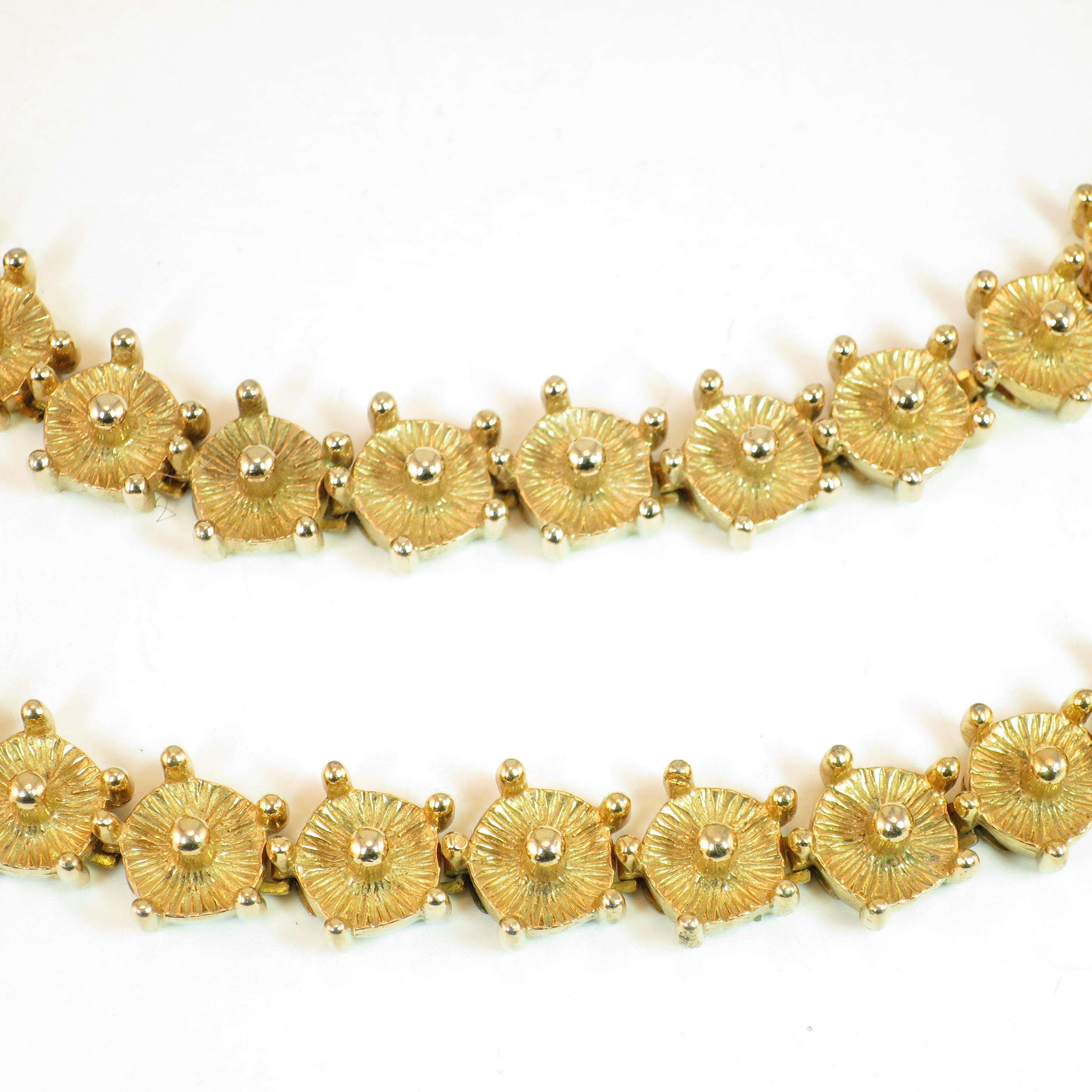 Offered here is a Mid-Century Modern Castlecliff choker necklace and matching bracelet suite from the 1960s. Both pieces are graced with bright gold plating, and present a segmented geometric design of linked round platforms with an etched radiating