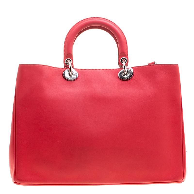 The Diorissimo bag from Dior is a timeless piece. The leather bag comes in a luxurious red hue with silver-tone hardware and Dior letter charms. It features double top handles, a detachable shoulder strap and protective feet at the bottom. A snap