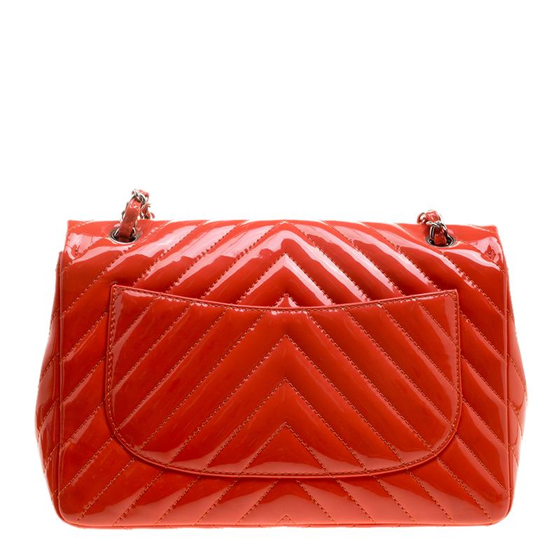 Crafted from glossy patent leather, this Chanel bag is a classic beauty. Its precious red coral exterior is designed with chevron quilting and is accented with silver-tone hardware. It features CC logo and has matching chain link and leather handles
