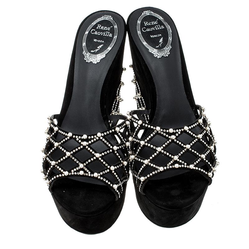 Set on a wedge sole, these Rene Caovilla slides goes perfectly well with trousers, dresses and even gowns. It features a black suede body with laser-cut detailing at the top. It is adorned with pearl and crystal embellishment at the vamps that make
