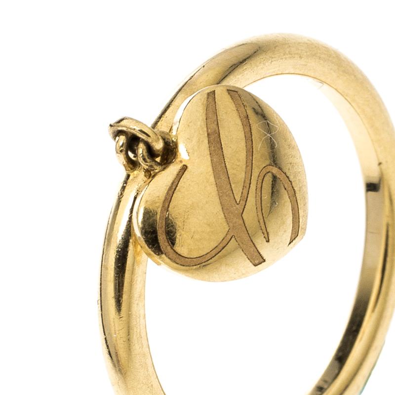 This Chopard ring has been crafted from 18k Yellow gold and styled with simple details to take your breath away. It comes in a sleek band with brand engravings and a dangling heart charm engraved with C. The piece has a royal appeal and it is bound