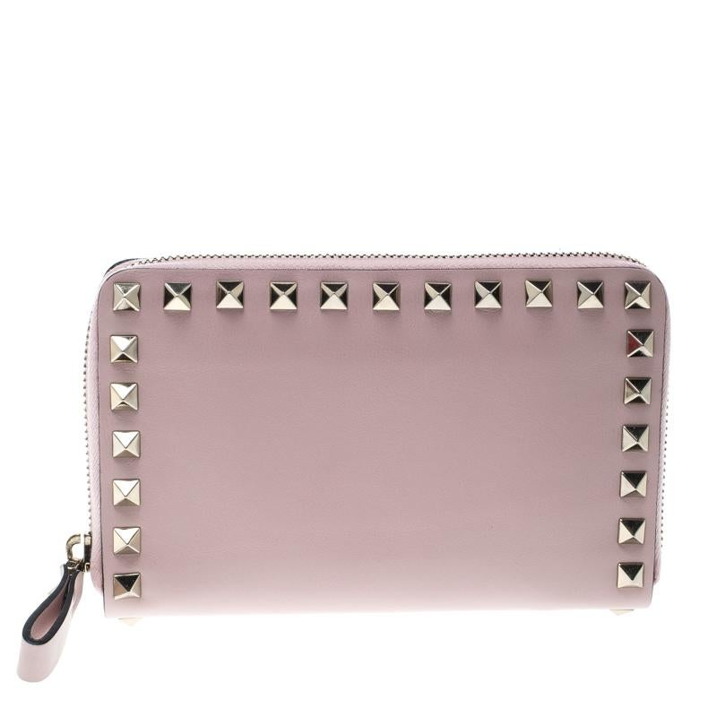 Bringing a blend of remarkable fashion and fine craftsmanship is this compact wallet from Valentino. The wallet comes crafted from pink leather and designed with pyramid studs and a zipper that opens to reveal multiple card slots and a zip