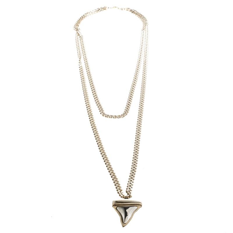 Don a bold look by complementing your outfits with this edgy necklace by Givenchy. Held by a chunky gold-tone two-tier chain, the necklace features a unique pendant carved in the shape of a shark tooth inlaid with silver-tone metal. It is complete