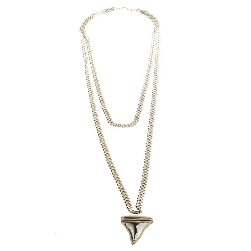 Don a bold look by complementing your outfits with this edgy necklace by Givenchy. Held by a chunky gold-tone two-tier chain, the necklace features a unique pendant carved in the shape of a shark tooth inlaid with silver-tone metal. It is complete