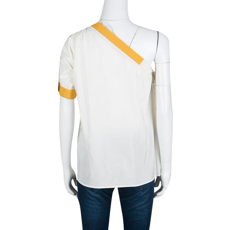 Cut to a stylish silhouette with one shoulder design; this Bottega Veneta top is perfect for your casual dos. It flaunts a cream hue with contrasting yellow trims. The top will work best with regular jeans, high heels, and a small shoulder