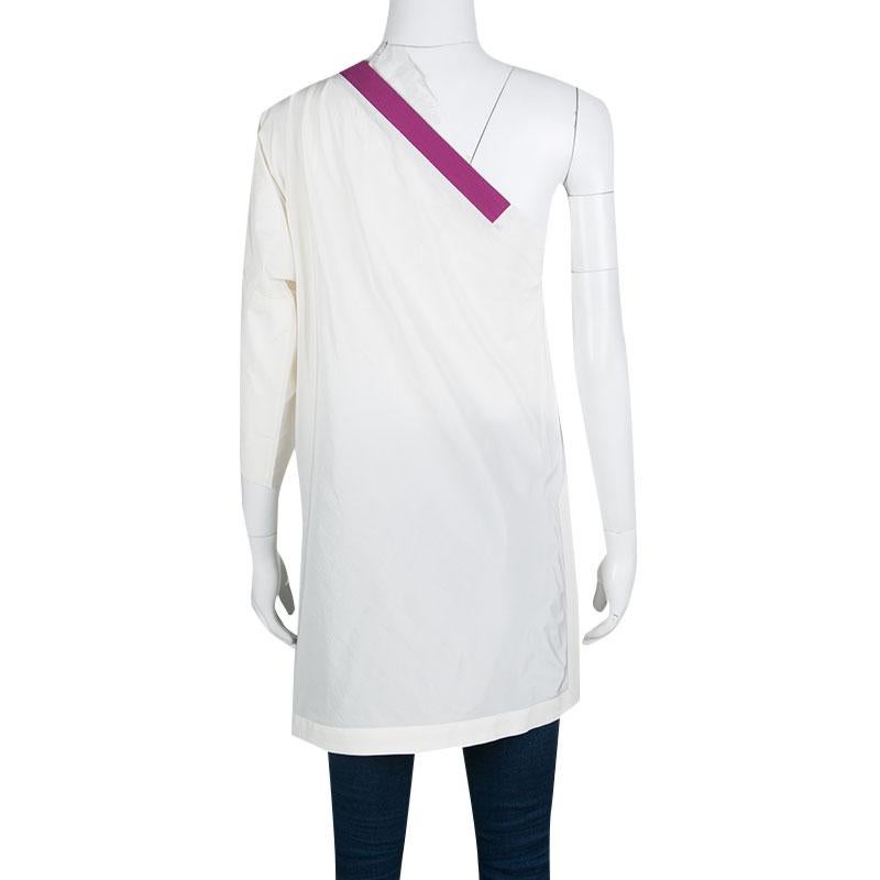 Cut to a stylish silhouette with one shoulder design; this Bottega Veneta tunic top is perfect for your casual dos. It flaunts a cream hue with contrasting purple trims. Crafted from a blend of cotton and silk, the top will work best with regular
