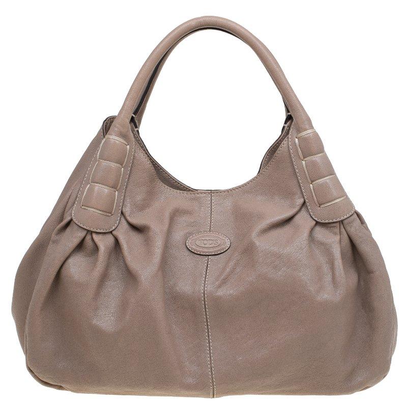 Die Ivy Sacca Media Tote Bag von Tod's ist ein atemberaubendes Stück aus beigefarbenem:: gekörntem Leder. Sie verfügt über zwei röhrenförmige Griffe mit Ziernähten am Boden und einem ovalen Aufnäher mit Logoprägung auf der Vorderseite. Das