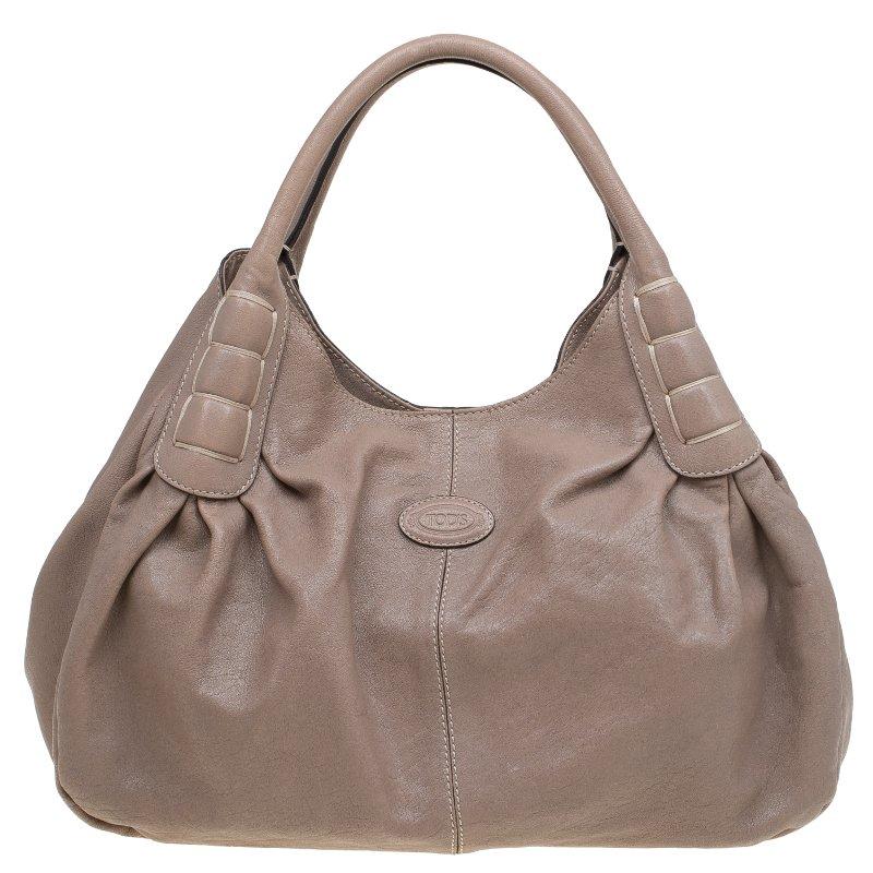 Tod’s Ivy Sacca Media tote bag is a stunning piece crafted from beige pebbled leather. It features dual tubular handles with decorative stitch detailing at the base and a logo stamped oval patch at front. A logo Jacquard textile lined-interior