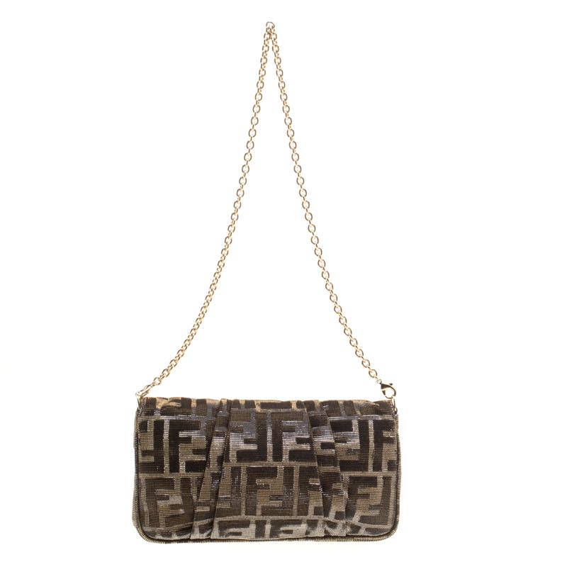 Look glamorous while carrying this shimmering Zucca Baguette chain clutch by Fendi. Crafted from metallic Zucca glitters, it features a front flap with the notable Fendi logo in gold-tone that opens a roomy interior lined with dark brown fabric and