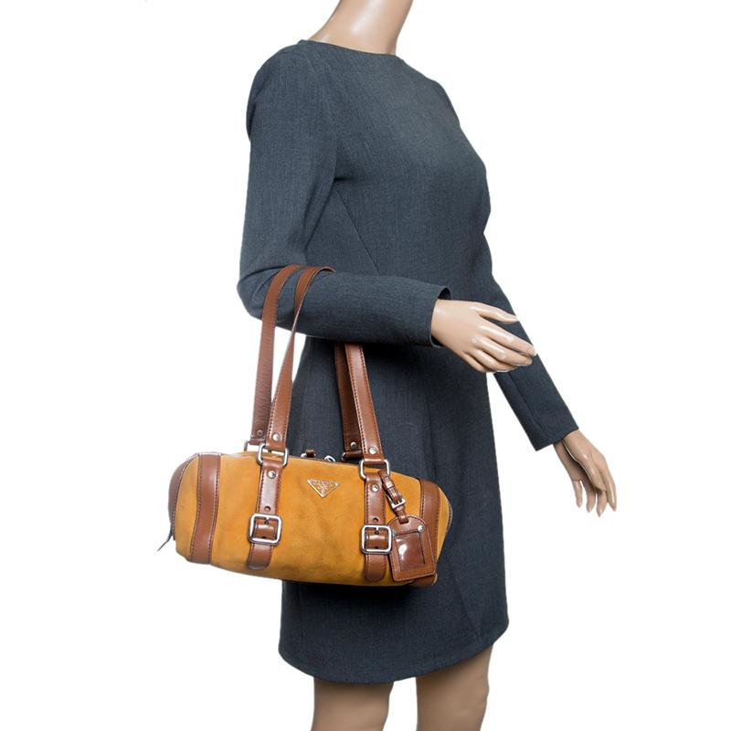 Prada introduces a classy piece of accessory for the progressive, sophisticated and fashionable woman. Crafted beautifully from suede and leather, it comes in a mix of yellow and brown, waiting for it to be grabbed. It is complete with two shoulder