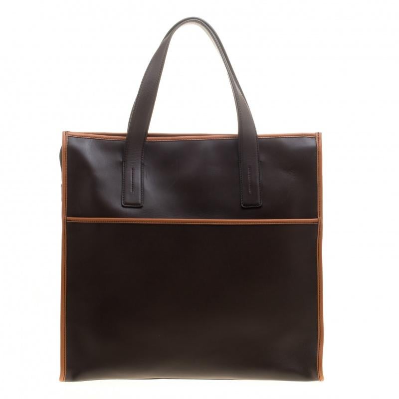 Featuring two handles at the top and a sleek dark brown exterior with hints of tan, this Tod's tote exudes just the right amount of luxury. The bag features protective feet and a capacious nylon compartment to house all your essentials. This piece