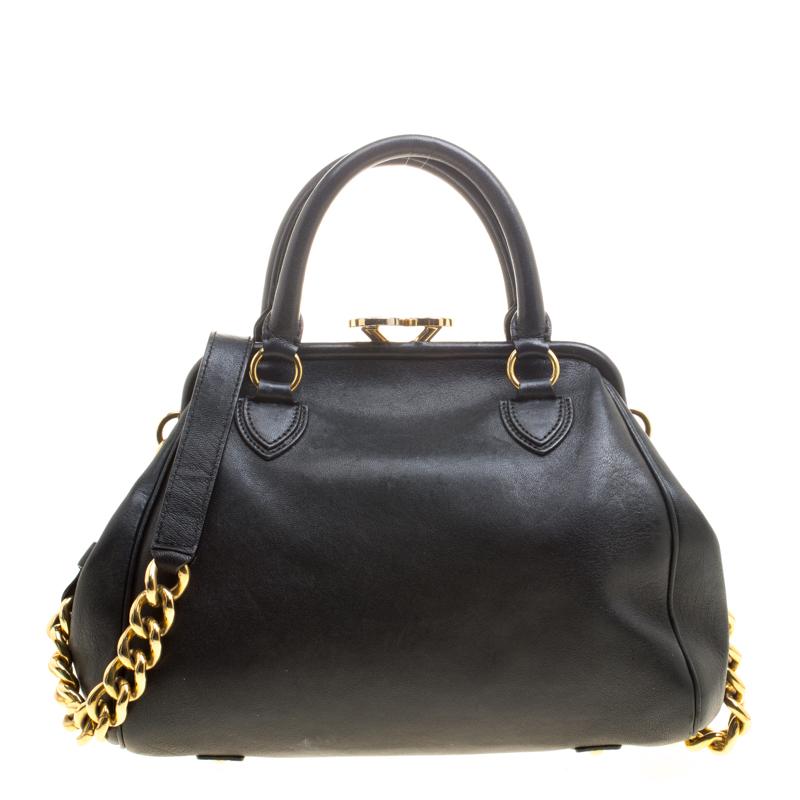 This Marc Jacobs Stam satchel is crafted from leather and features black exterior. The bag has a kiss lock closure, dual handles, a front zip pocket, protective metal feet and a detachable chain strap with leather shoulder rest. The canvas lined