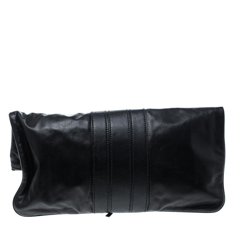 'Lucy' clutch by Gucci is both glamorous and functional. Featuring a fold-over silhouette, this clutch is made of black leather and has bamboo details on the turn lock closure. The top zip closure with a tassel detail opens to a spacious