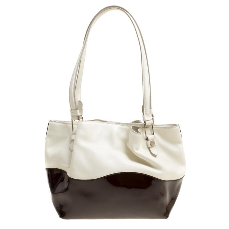 Elevating your look with a contemporary design is this Flower tote from Tod's. This bag has a lovely exterior which is a combination of white leather and brown patent leather. This tote is equipped with a spacious nylon-lined interior that can