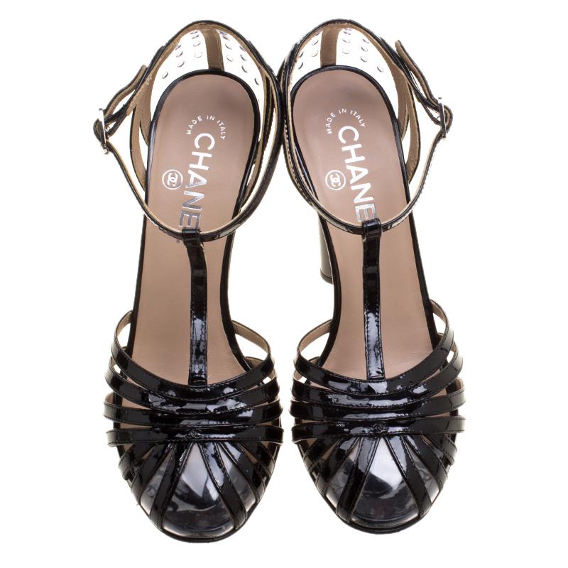 Add the perfect finishing touch to your evening look with these black patent leather Chanel T-strap sandals. These stunning footwear come with clear PVC accents throughout, tonal stitching, resin block heels and silver-tone buckle closures at