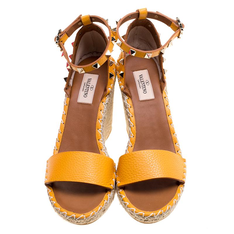 Valentino surely knows how to win hearts by bringing out this chic stud embellished wedges with uber-convenient ankle straps. With elevated heels that are designed as trendy espadrilles and an eye-catching tangerine colour, this pair of wedge