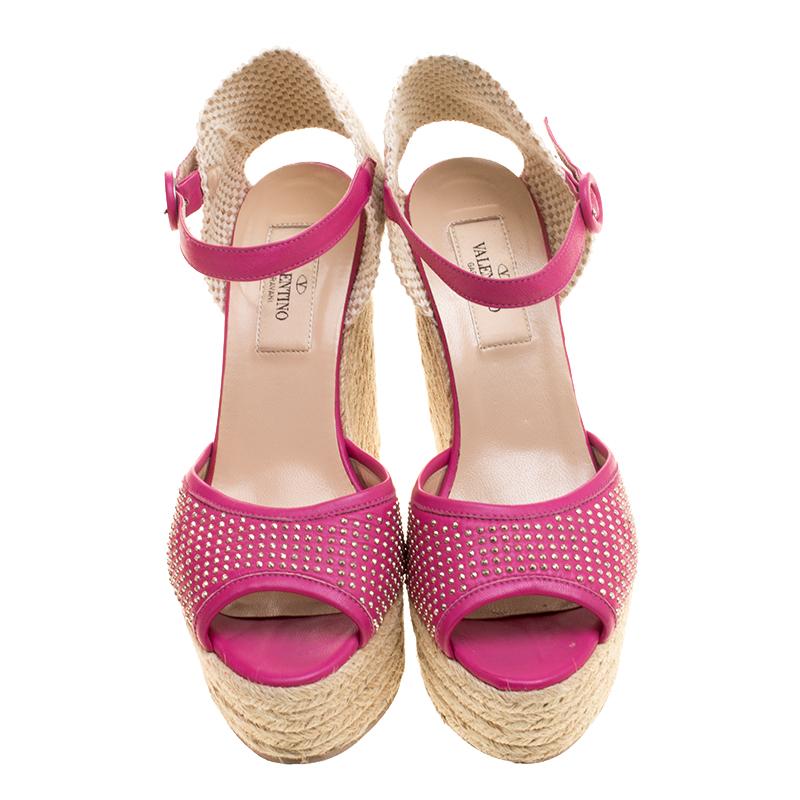 Complete your summer look with these Valentino sandals. Crafted with leather, the pair features pink studded strap on the front along with buckled ankle straps and lace counters detailed with cutouts. This lovely pair has espadrille wedges elevated