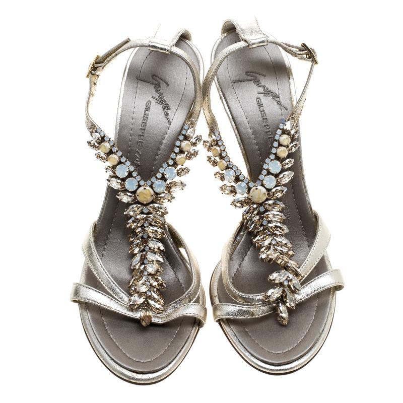 Give a glamorous finish to your look by stepping out in these stunning sandals from the house of Giuseppe Zanotti. Crafted from metallic light gold leather, this pair features a T-strap beautifully embellished with crystals and buckle fastening at