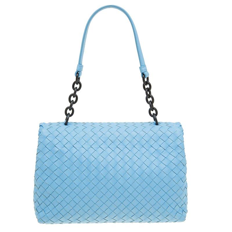 Complete your fun day look with this visually appealing baby blue Olimpia bag by Bottega Veneta. Crafted from signature intrecciato leather, it features a flap closure and a single top handle with black-tone hardware. The suede lined interior