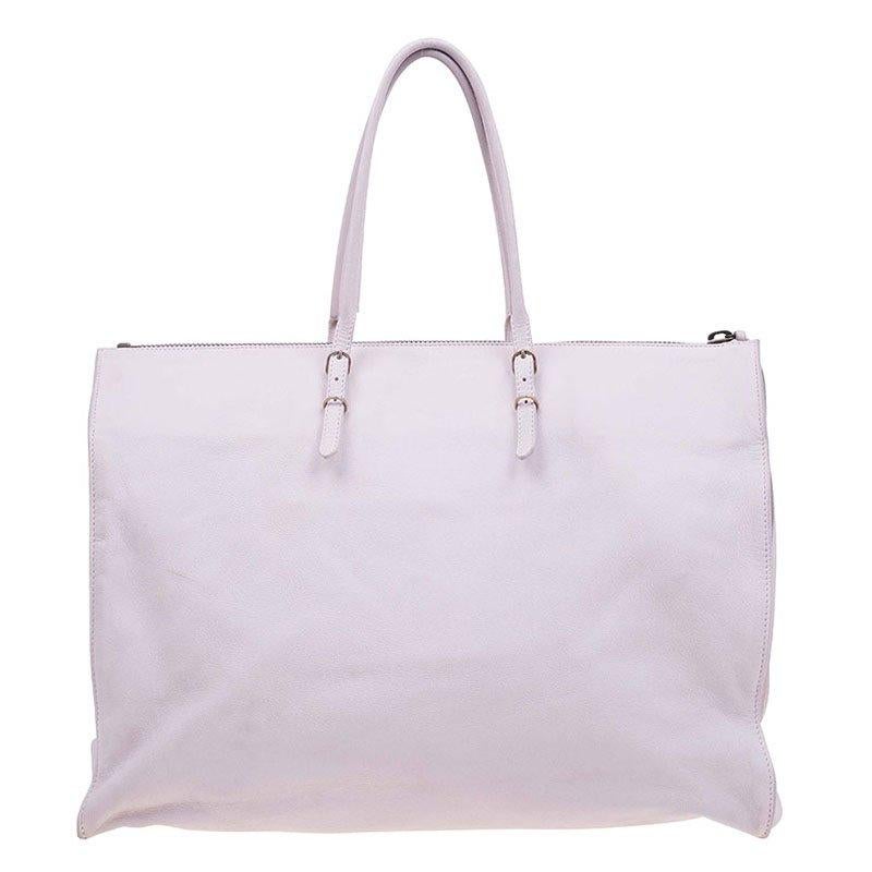 Balenciaga Papier A4 Tote interprets the label's modern aesthetic with an edge. Made in Italy from calfskin leather, this tote is topped with shoulder straps with buckle detailing. Accented with aged brass hardware, it features a front zip pocket