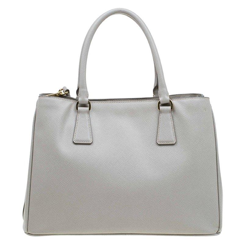 This leather bag is an evidence why Prada is synonymous with fashion. An elegant and sophisticated creation from Prada, this two-strap tote bag is made to flaunt. Made of Saffiano lux leather, the bag features two spacious interior compartments and