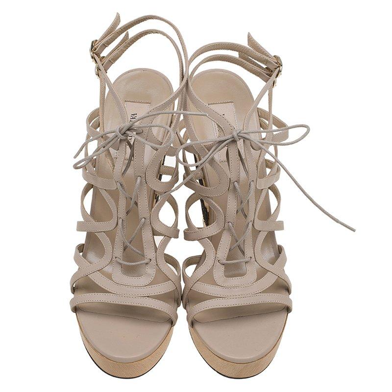 Detailed wedges by Valentino are feminine yet bold! Beige in color the peep toe design is accented with a high cut lace up vamps extend into an ankle tie closure. The quarter panels and the counters have a delicate floral lace detail. A high shank