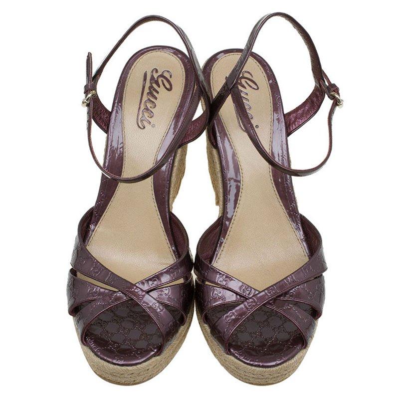 Penelope' espadrille from the house of Gucci is designed in a gorgeous plum purple patent leather, embossed with micro Guccissima. It is set on a high braided jute wedge heel and secured with an ankle strap buckle closure. We think it makes a