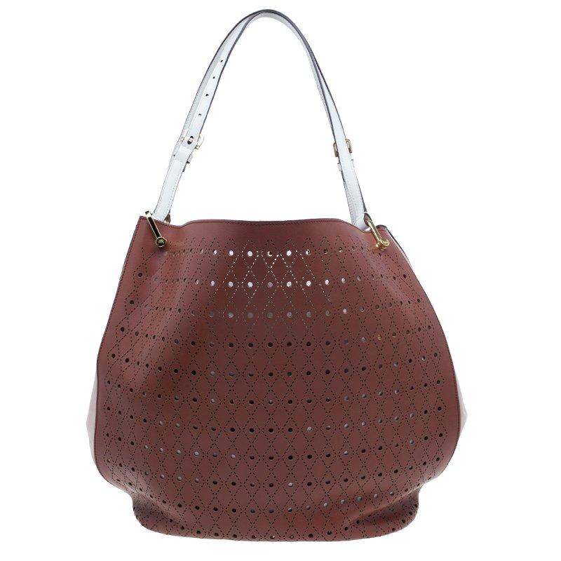 An excellent bag to glam up any outfit, this tote + clutch from Tod's signature Secchiello collection is versatile. It is crafted from beautiful perforated leather in two tones. The exterior features adjustable handles and the base is protected with
