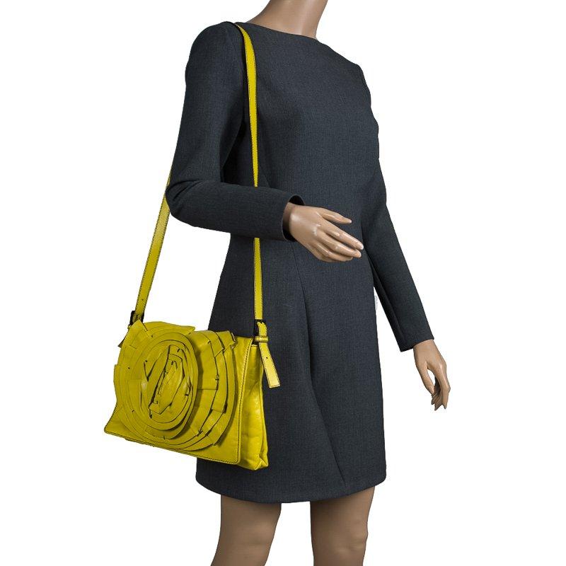 The fluorescent yellow leather Petale shoulder bag from Valentino can easily jazz up your summer looks! The front is adorned with concentric circles held using black tacks.The bag opens to a roomy satin interior that houses another zip closure.